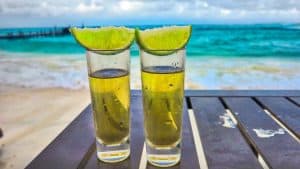 Refreshing tequila shots with lime wedges on a beachside table, perfect for relaxing by the ocean at Cozumel.