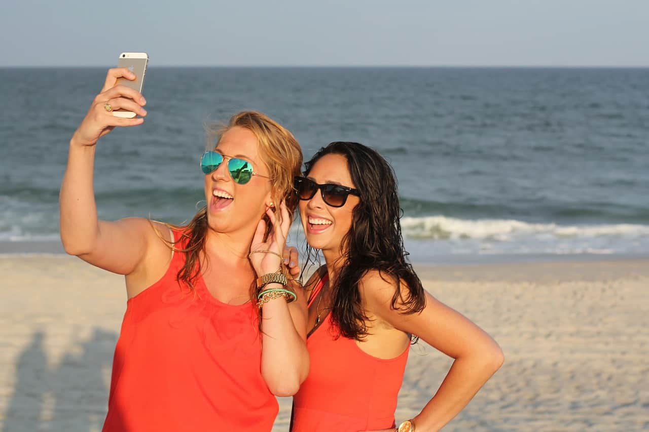 Bright women taking a selfie on the beach in Cozumel, Mexico, enjoying sunny weather, turquoise waters, and the stunning Caribbean scenery near Stingray Villa vacation rental.