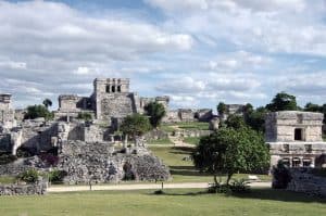 Ancient Mayan ruins at Chichen Itza in Mexico with lush greenery and blue sky.