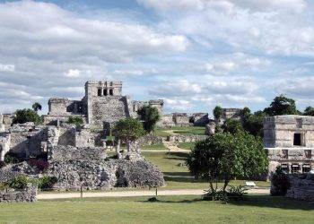 Ancient Mayan ruins at Chichen Itza in Mexico with lush greenery and blue sky.