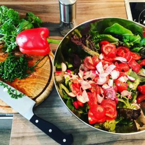 Fresh vegetable salad with cherry tomatoes, sliced onions, and leafy greens prepared in Cozumel Mexico.