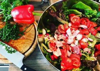 Fresh vegetable salad with cherry tomatoes, sliced onions, and leafy greens prepared in Cozumel Mexico.