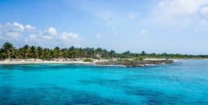 Cozumel Mexico beach view near Stingray Villa vacation rental with turquoise waters and lush palm trees.