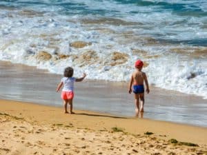 Kids playing on the sandy beach in Cozumel Mexico near Stingray Villa vacation rental. Family-friendly seaside retreat with clear waters, perfect for a tropical getaway.