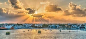 Vibrant sunrise over Cozumel Mexico waterfront with boats, cruise ships, and colorful buildings, showcasing the beauty of Stingray Villa vacation rental and the lively coastal scenery.