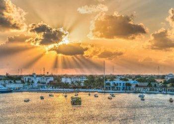 Vibrant sunrise over Cozumel Mexico waterfront with boats, cruise ships, and colorful buildings, showcasing the beauty of Stingray Villa vacation rental and the lively coastal scenery.