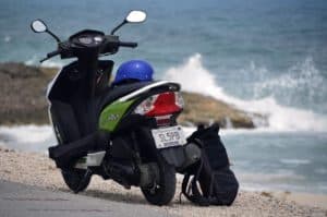 Motor scooter parked on the beach in Cozumel Mexico with the ocean and rocky coastline in the background.