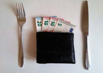 Euro banknotes inside a black wallet, placed between a fork and a knife, representing affordable vacation rentals at Stingray Villa in Cozumel Mexico.