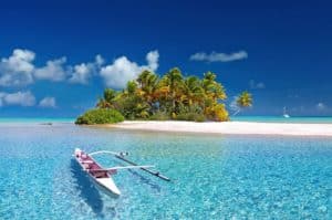 Azure waters and white sandy beach near Stingray Villa in Cozumel Mexico with a small boat floating near lush palm trees. Perfect tropical vacation rental for exploring Caribbean paradise.