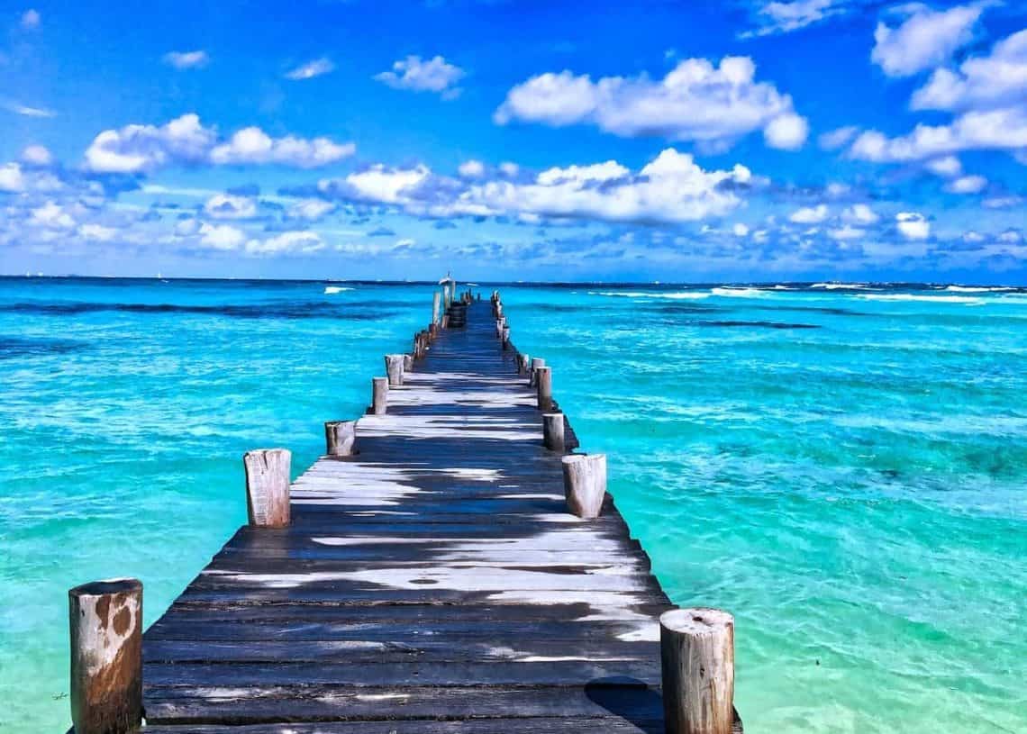 Serene wooden pier extending into clear turquoise waters of Cozumel, Mexico, perfect for relaxing vacation rentals at Stingray Villa.