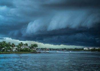 Stormy sky over Cozumel waterway with luxury vacation rentals and lush palm trees.