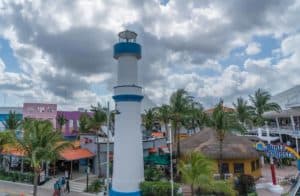 Colorful tropical scenery of Cozumel Mexico featuring the Punta Langosta lighthouse, vibrant buildings, and lush palm trees near Stingray Villa vacation rental.