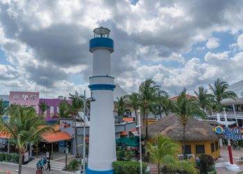 Colorful tropical scenery of Cozumel Mexico featuring the Punta Langosta lighthouse, vibrant buildings, and lush palm trees near Stingray Villa vacation rental.