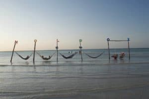 Colorful hammocks and swings on Holbox Mexico beach near Stingray Villa vacation rental, offering relaxing oceanfront views and inviting seaside relaxation experiences.