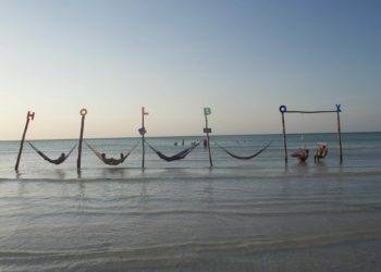 Colorful hammocks and swings on Holbox Mexico beach near Stingray Villa vacation rental, offering relaxing oceanfront views and inviting seaside relaxation experiences.
