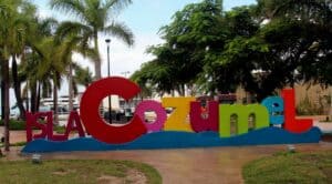 Colorful Isla Cozumel sign with palm trees and marina in the background, showcasing the vibrant tropical atmosphere of Cozumel, Mexico, perfect for vacation rentals like Stingray Villa.