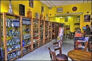 An indoor tequila shop near Stingray Villa, Cozumel Mexico, featuring a wide selection of tequila bottles with vibrant yellow walls and wooden shelving.