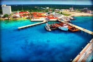Vibrant aerial view of Cozumel Mexico marina showcasing colorful buildings, cruise ships, boats, and clear turquoise waters near Stingray Villa vacation rental.