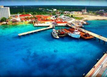 Vibrant aerial view of Cozumel Mexico marina showcasing colorful buildings, cruise ships, boats, and clear turquoise waters near Stingray Villa vacation rental.