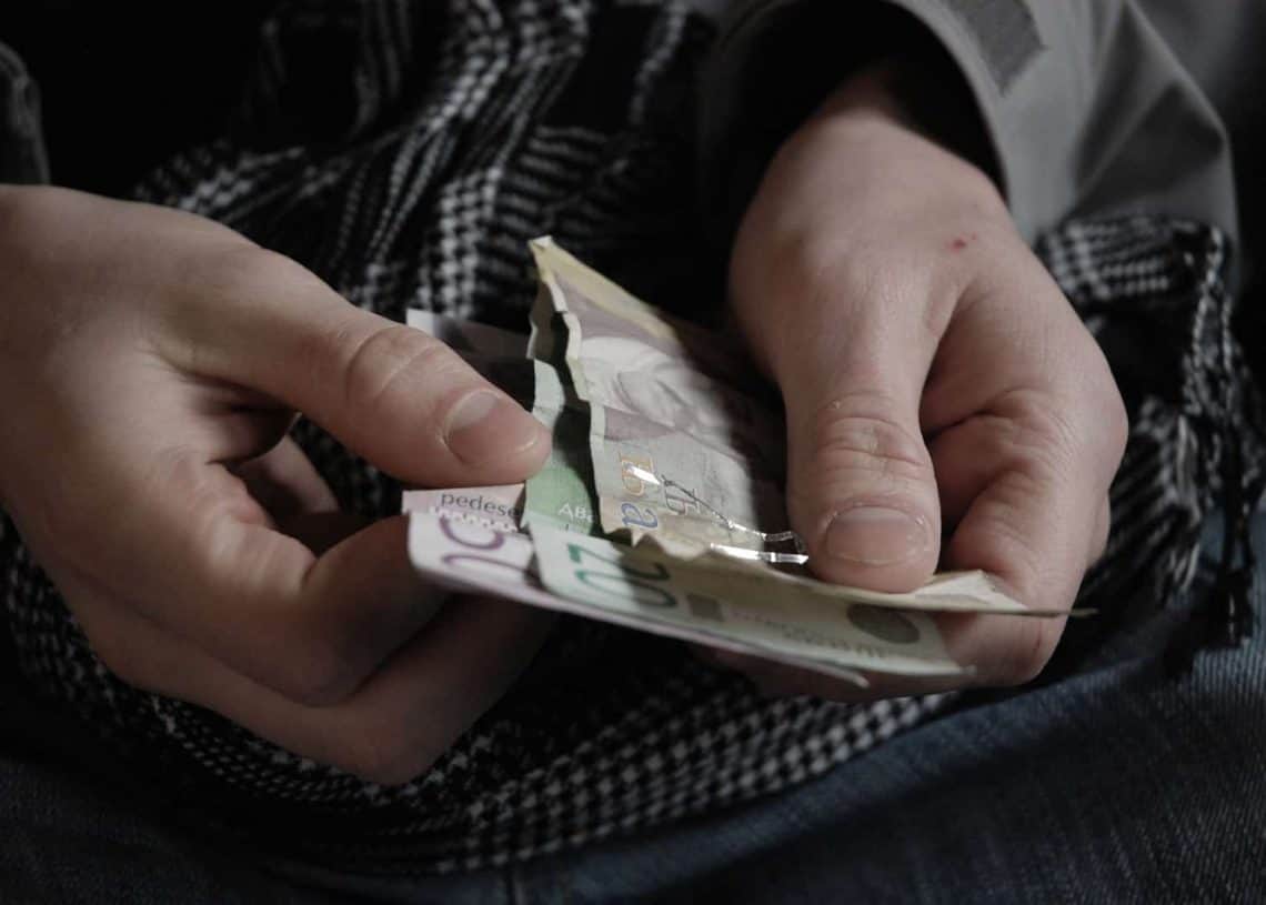 A close-up of hands with a peso banknote, emphasizing how to save money for travelers in Cozumel.