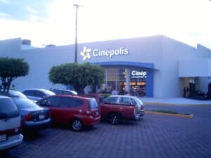 Spacious parking lot with cars in front of Cinépolis cinema, a popular entertainment destination in Cozumel, Mexico.