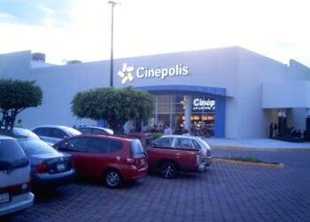 Spacious parking lot with cars in front of Cinépolis cinema, a popular entertainment destination in Cozumel, Mexico.