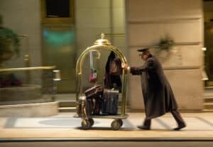 Luggage porter pushing a cart with suitcases and bags outside a hotel in Cozumel, Mexico, near Stingray Villa vacation rentals. Perfect for travel and vacation getaway SEO keywords.
