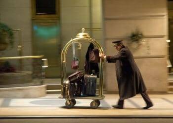 Luggage porter pushing a cart with suitcases and bags outside a hotel in Cozumel, Mexico, near Stingray Villa vacation rentals. Perfect for travel and vacation getaway SEO keywords.