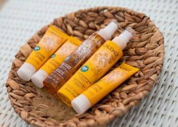 Bright yellow and brown Caudalie sunscreen bottles in a wicker basket at Cozumel Mexico, for sun protection during beach vacation.