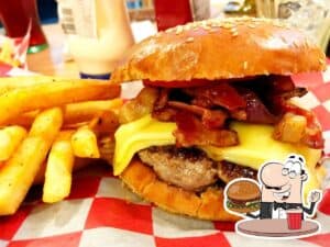Juicy bacon cheeseburger with melted cheese, crispy bacon, and fresh toppings served with golden French fries at Faro burger, in Cozumel, Mexico.