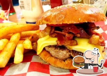 Juicy bacon cheeseburger with melted cheese, crispy bacon, and fresh toppings served with golden French fries at Faro burger, in Cozumel, Mexico.