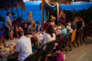 Beachfront dinner at Cozumel Mexico with ocean views, tropical decor, and a lively gathering of guests enjoying a memorable sunset celebration.