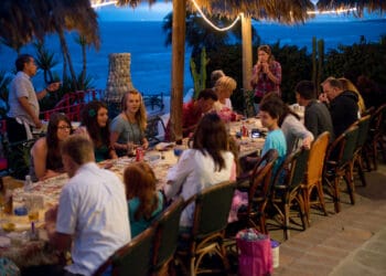 Beachfront dinner at Cozumel Mexico with ocean views, tropical decor, and a lively gathering of guests enjoying a memorable sunset celebration.