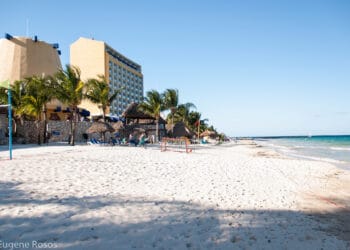 Cozumel Mexico beach view at Melia Resort, featuring white sand, turquoise waters, palm trees, and beachfront hotels. Perfect for relaxing oceanfront vacation in Cozumel.