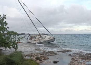 Sailboat grounded on the rocky shoreline near Cozumel, Mexico, with overcast skies, during a norte storm.