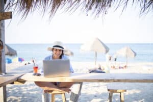 Relaxing woman working on laptop while on a Workation in Cozumel Mexico. Enjoy ocean views, tropical shade, and serene Caribbean ambiance.