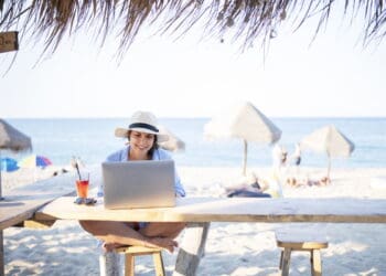 Relaxing woman working on laptop while on a Workation in Cozumel Mexico. Enjoy ocean views, tropical shade, and serene Caribbean ambiance.