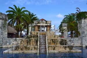 Lush tropical palm trees surround a decorative stone fountain in a tropical Puerta Maya Cozumel setting