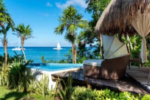 Luxurious tropical VRBO with ocean view and private infinity pool, surrounded by lush greenery, perfect for a relaxing beachfront vacation.