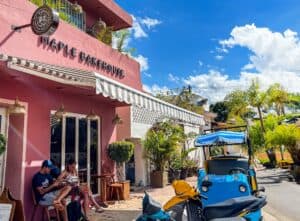 Colorful Pink Building of Maple Bakehouse with outdoor seating and tropical plants in sunny weather