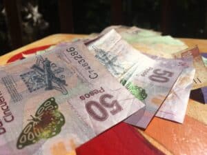 Peso banknotes displayed outdoors on a wooden surface.