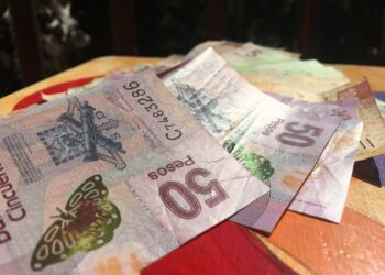 Peso banknotes displayed outdoors on a wooden surface.