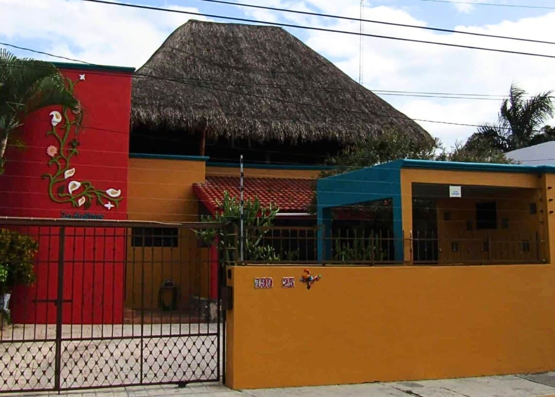 Colorful vacation rental house in Cozumel, Mexico with vibrant walls, tropical decor, and a thatched roof.