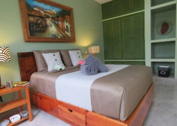 A bed with a white and brown bedspread and a painting on the wall.