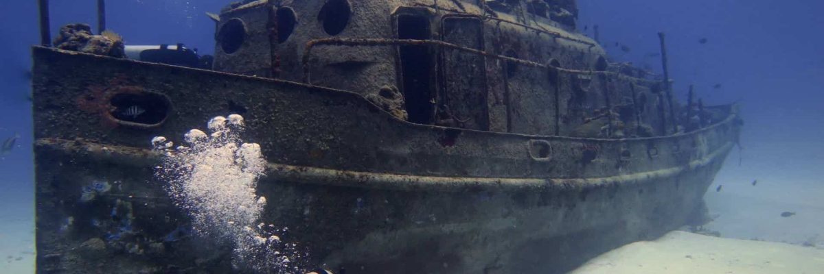 Wrecked ship underwater near Cozumel, Mexico, with scuba diver exploring the scenic ocean ruins.
