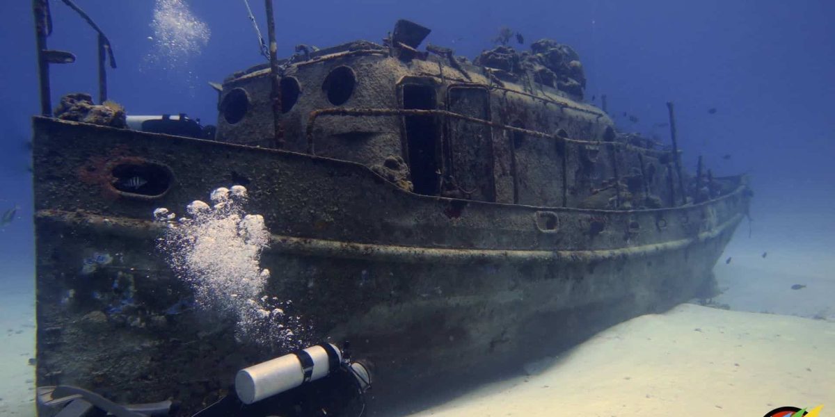 Wrecked ship underwater near Cozumel, Mexico, with scuba diver exploring the scenic ocean ruins.