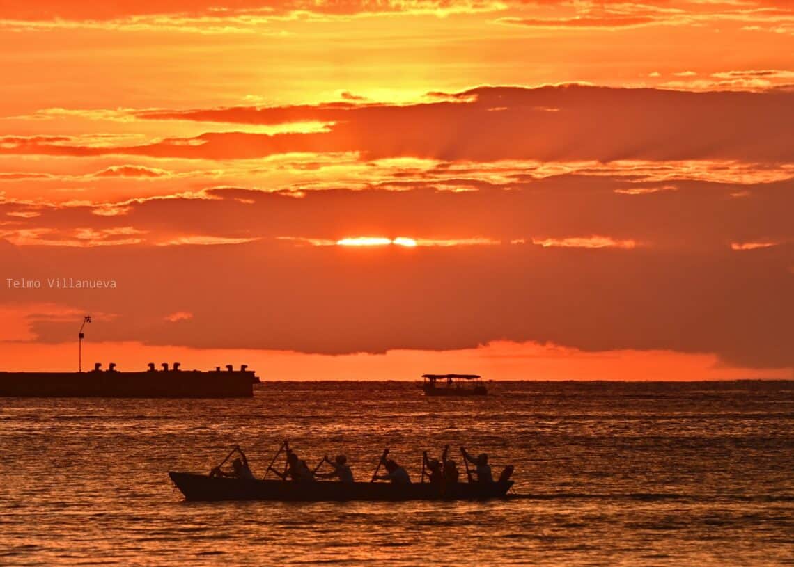 Beautiful sunset over Cozumel Mexico with a boat silhouette on the calm ocean, perfect for vacation rentals at Stingray Villa.